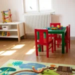 Gruppenraum mit kleinen Kindertischchen und Regal mit spielzeug