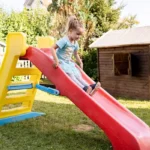 Mädchen rutscht eine kleine Plastikrutsche hinab