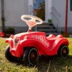 Roter Bobbycar auf grüner Wiese