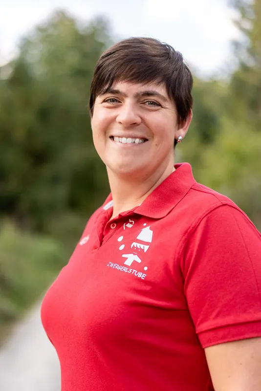 Frau mit rotem Shirt, kurzen schwarzen Haaren, lächelt